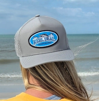 Person wearing a gray cap with a logo on a beach